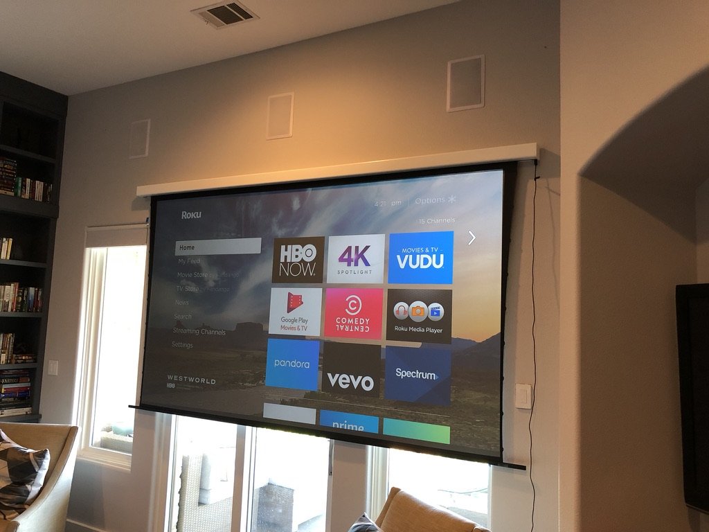 Motorized projection screen lowered in front of a window